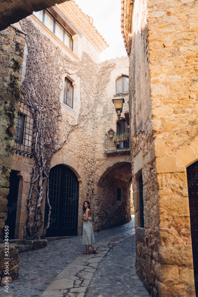 Chica paseando por antiguas calles de piedra y flores en Pals, provincia de Girona, Costa Brava