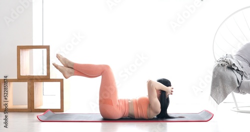 Slim sporty girl doing v-ups abs workout at home.