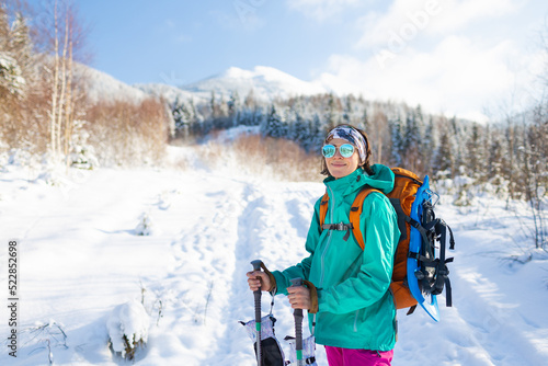 A woman walks with snowshoes on the backpack