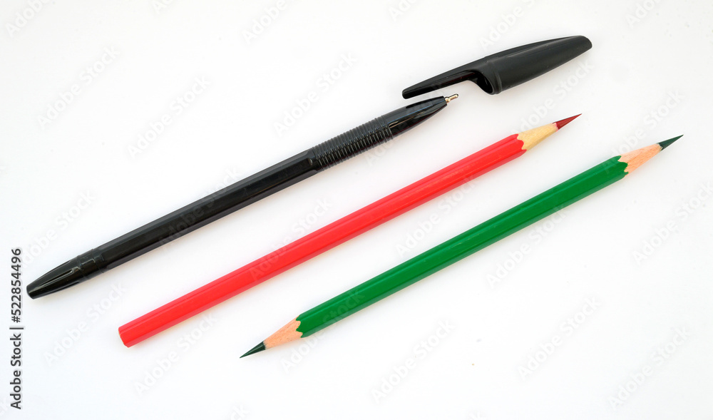 black pen and two graphite pencils in red and green on a white background black pen and two graphite pencils in red and green on a white background