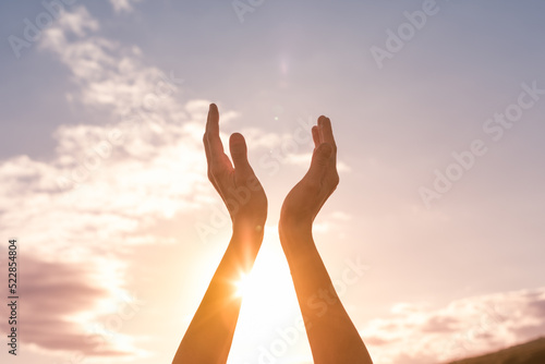 Hands up touching the sunlight. Spiritual, light, and prayer concept. 