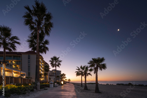 A beach path on Coronado beach  San Diego  at sunrise.  The sky is turning orange and the moon can still be seen in the sky. 