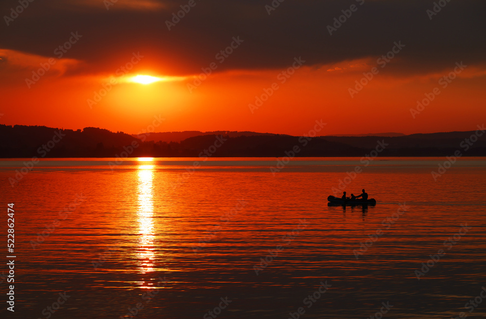 Beautiful orange sunset at Sempach Lake, Switzerland. Sunset sky image of tropical sunset. Summer vacation travel card or banner template

