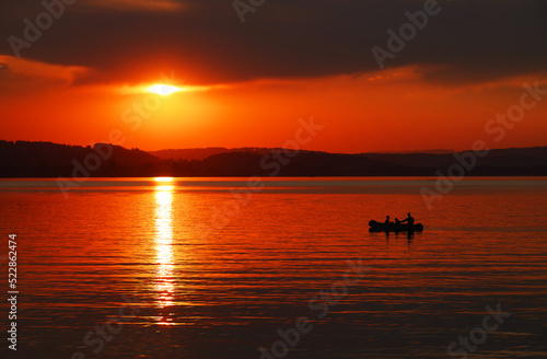 Beautiful orange sunset at Sempach Lake, Switzerland. Sunset sky image of tropical sunset. Summer vacation travel card or banner template 