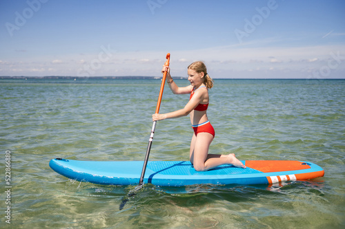 Beautiful child girl practice paddling on surfboard in sea at summer © spass