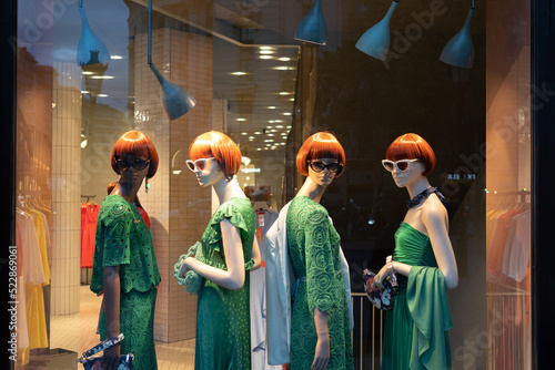 Female mannequins wearing stylish green clothes collection. Dummies in the store window. Fashion & Style storefront