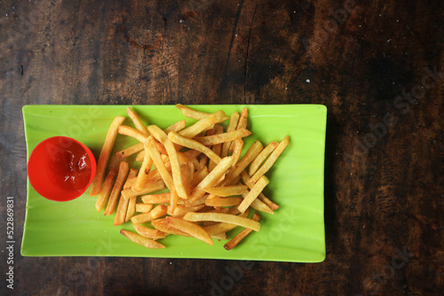 Fresh French fries in a bowl on old grunge dark textured wooden background
