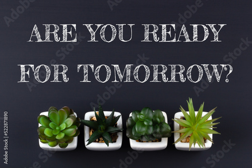 Text ARE YOU READY FOR TOMORROW? on black chalkboard with green plants. Business concept.