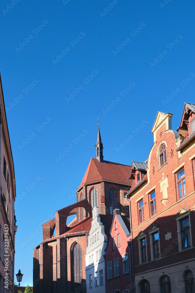Historic buildings and back side of St. Nicholas Church in Wismar, Germany with blue sky.