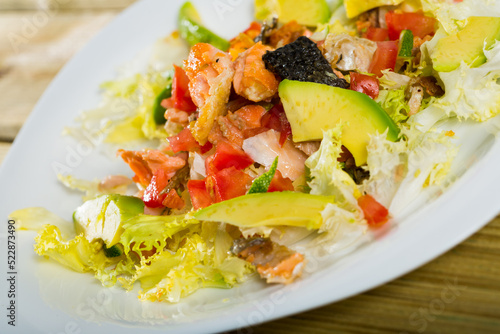 Fresh colorful salad with grilled salmon, ripe avocado, tomatoes, lettuce leaves and lemon..