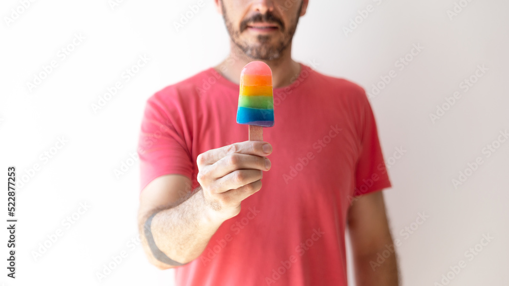 gay man holding an ice cream with the color of the rainbow, symbol of the LGTBI collective gay man holding an ice cream with the color of the rainbow, symbol of the LGTBI collective