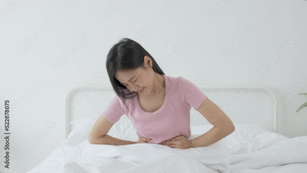 Young asian woman sitting on bed pain stomach or bowel with disease constipation in the bedroom at home, unhappy female sick and menstruation and stomachache, medical and health concept. Young asian woman sitting on bed pain stomach or bowel with disease constipation in the bedroom at home, unhappy female sick and menstruation and stomachache, medical and health concept.