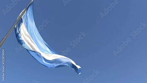 Bandera Argentina flameando con mucho viento y cielo azul