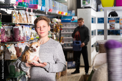 Portrait of a boy with dog in petshop, man on background. High quality photo © JackF