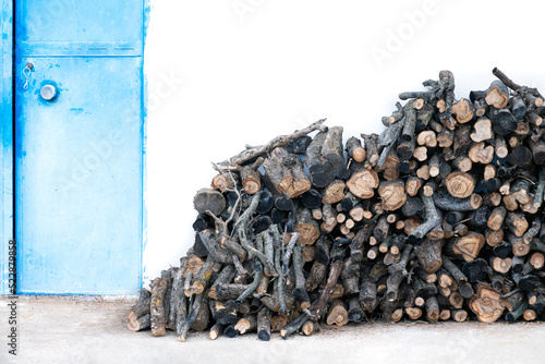 Stack of Firewood Next to a Blue Metal Door