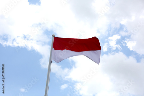 Indonesian flag flying on pole against blue sky
