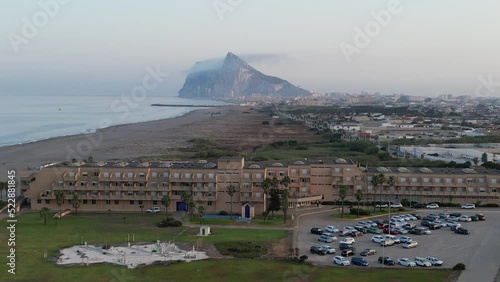 Sunset drone shot rising up and zoomed in above beach resort looking south towards Africa from Spain with the rock of Gibraltar in view.