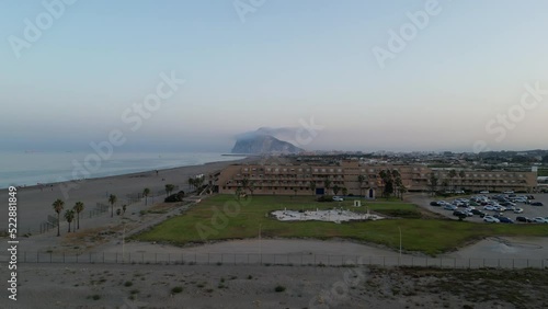 Sunset drone shot rising up above beach resort looking south towards Africa from Spain with the rock of Gibraltar in view.