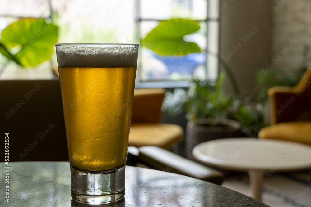 glass of beer on a terrazzo table, two yellow chairs in the background, retro table, window with natural light glass of beer on a terrazzo table, two yellow chairs in the background, retro table, window with natural light