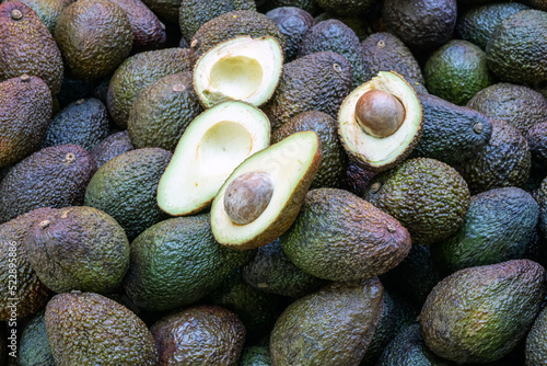 Avocados for sale on a market with to halfed ones photo