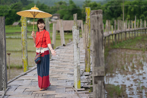 Asian woman dressed in traditional Northern Thailand culture on the longest bamboo bridge (Su Tong Pae bridge) at Suan Tham Phu Sama temple in Mae Hong Son, Thailand.