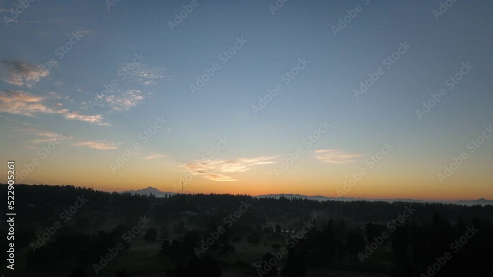 Panning aerial shot of the sun rising over Whidbey Island's Oak Harbor community with Mount Baker off in the distance. Panning aerial shot of the sun rising over Whidbey Island's Oak Harbor community with Mount Baker off in the distance.