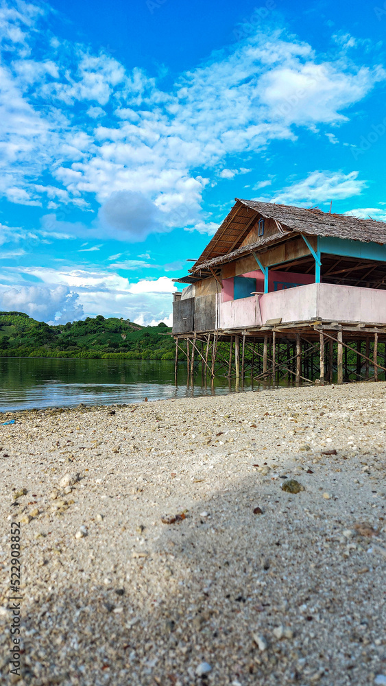 Obraz premium A simple plank house made of wood and poles using tree trunks stands firmly on the edge of the beach. It is located at Ratu Beach, Boalemo Regency, Gorontalo Province. Outdoor photo taken on August