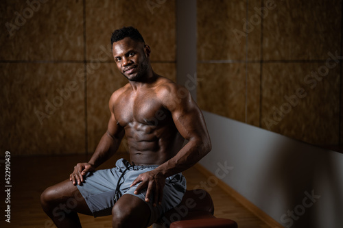 Handsome afro american shirtless man posing in the gym. 