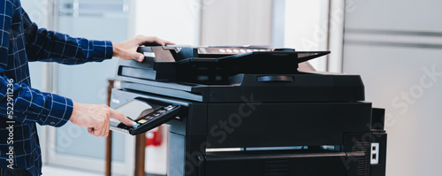 Copier printer, Close up hand office man press copy button on panel to using the copier or photocopier machine for scanning document printing a sheet paper. photo