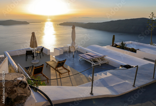 Sun loungers on terrace in the village of Imerovigli with amazing view of sunset over caldera in Santorini, Greece photo