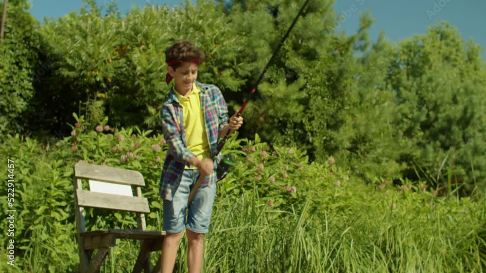 Excited cute school age Arab fisherman boy catching fish with spin fishing rod from jetty on lake, enjoying angling and recreational activity in summer nature. Excited cute school age Arab fisherman boy catching fish with spin fishing rod from jetty on lake, enjoying angling and recreational activity in summer nature.