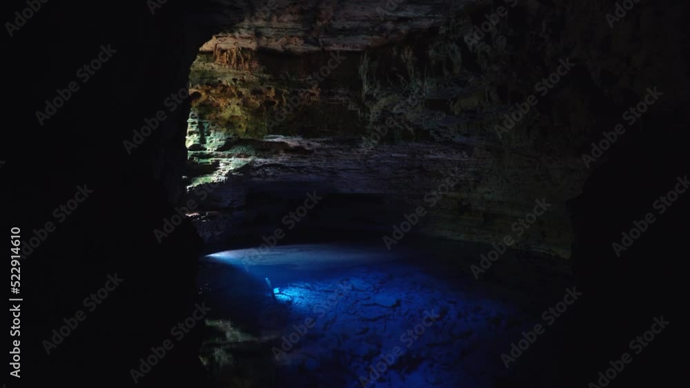 Tilting up shot of the incredible stunning natural cave pool the Enchanted Well or Poço Encantado in the Chapada Diamantina National Park in Northeastern Brazil with beautiful clear blue water. Tilting up shot of the incredible stunning natural cave pool the Enchanted Well or Poço Encantado in the Chapada Diamantina National Park in Northeastern Brazil with beautiful clear blue water.