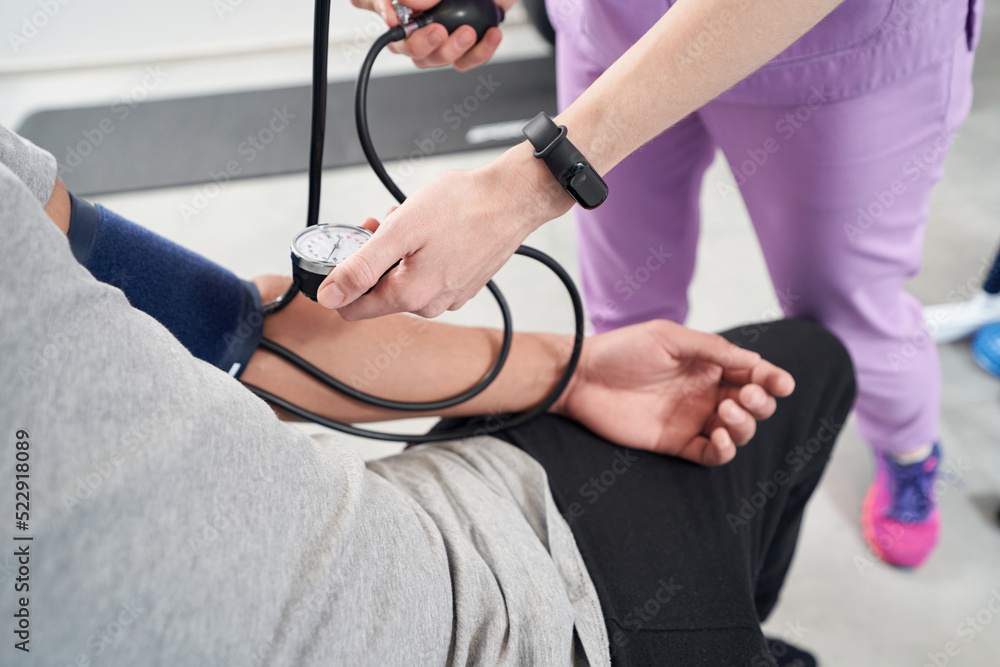 Female doctor measuring patient blood pressure in clinic
