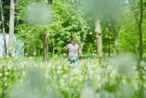 A school-age girl in a meadow with dandelions. Recreation in the park. © Fotoproff