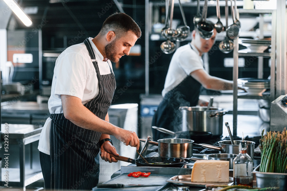 In uniform. Kitchen workers is together preparing the food In uniform. Kitchen workers is together preparing the food