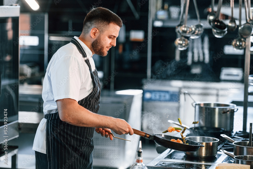 Flames on the frying pan. Chef is on the kitchen preparing food