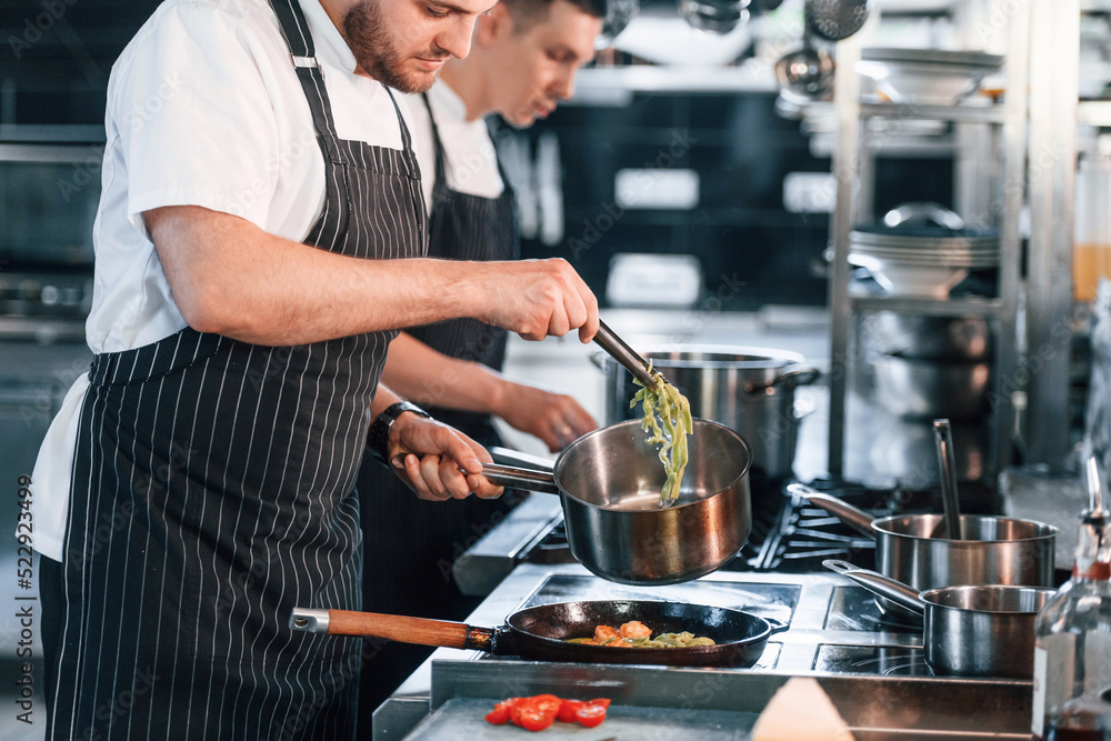 Side view. Kitchen workers is together preparing the food Side view. Kitchen workers is together preparing the food
