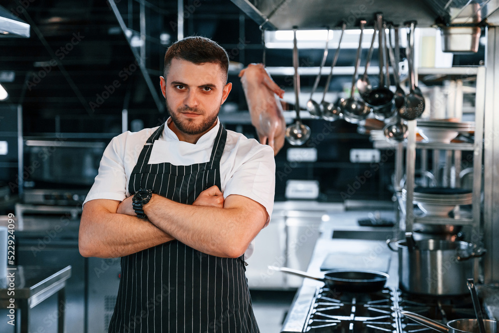Standing with arms crossed. Chef is on the kitchen preparing food Standing with arms crossed. Chef is on the kitchen preparing food