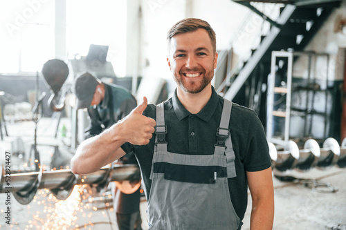 Standing and smiling. Man in uniform is in workstation developing details of agriculture technique