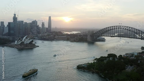 Aerial Panning Left Over Iconic Harbor With Passing Boats At Sunset - Sydney, Australia photo
