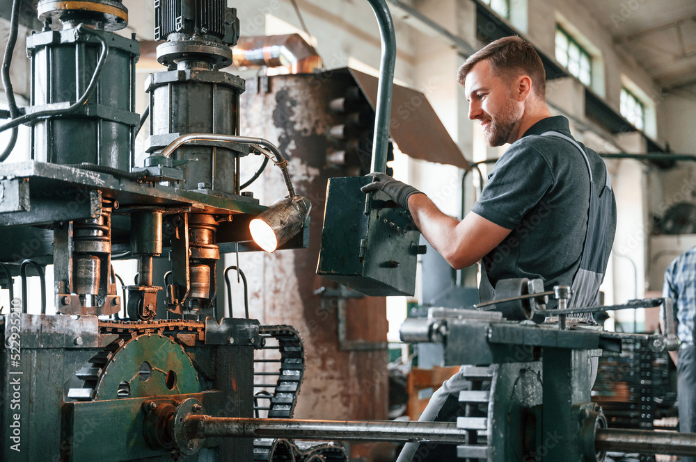 Metal processing device. Man in uniform is in workstation developing details of agriculture technique Metal processing device. Man in uniform is in workstation developing details of agriculture technique