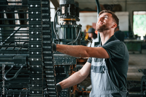 Metal processing device. Man in uniform is in workstation developing details of agriculture technique