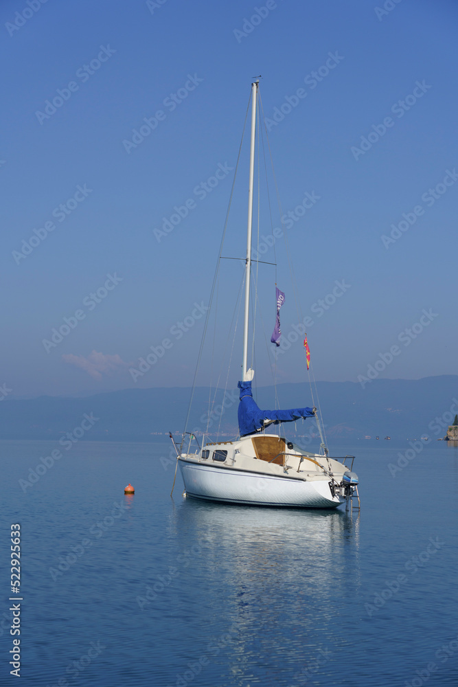 Albania, May 12, 2022 - Sail boat and reflection anchored near shore. Albania, May 12, 2022 - Sail boat and reflection anchored near shore.