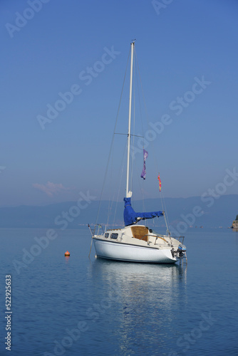 Albania, May 12, 2022 - Sail boat and reflection anchored near shore.