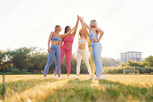 Giving high five. Group of women have fitness outdoors on the field together