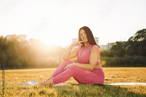 Wallpaper Mural In pink clothes. Sitting on the ground. Beautiful woman in sportive clothes doing fitness exercises outdoors on the field Torontodigital.ca