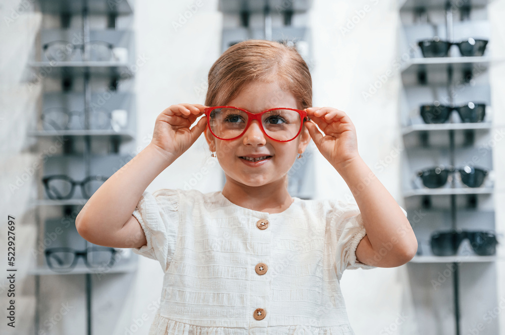 Portrait of little girl that is in the glasses store choosing eyewear Portrait of little girl that is in the glasses store choosing eyewear