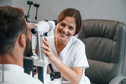 Modern technologies. Man's vision checked by female doctor in the clinic by using special optometrist device