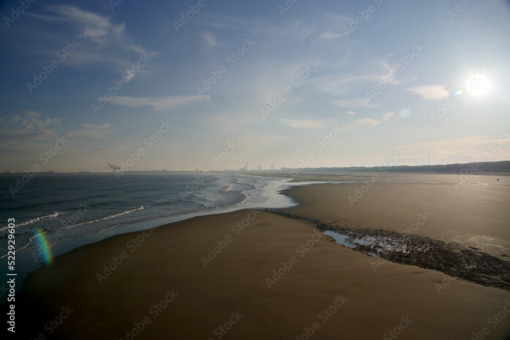 Morning view of a sunny beach with port in the back