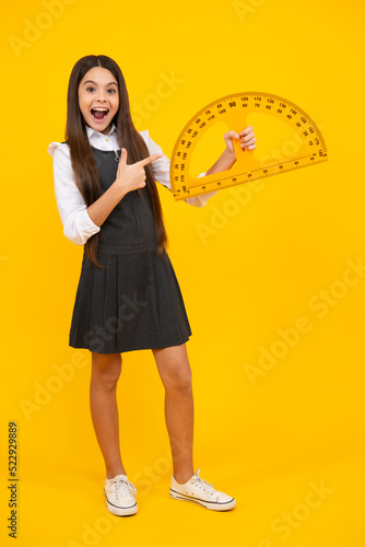Back to school. School girl hold ruler measuring isolated on yellow background. Excited face, cheerful emotions of teenager girl. © Olena
